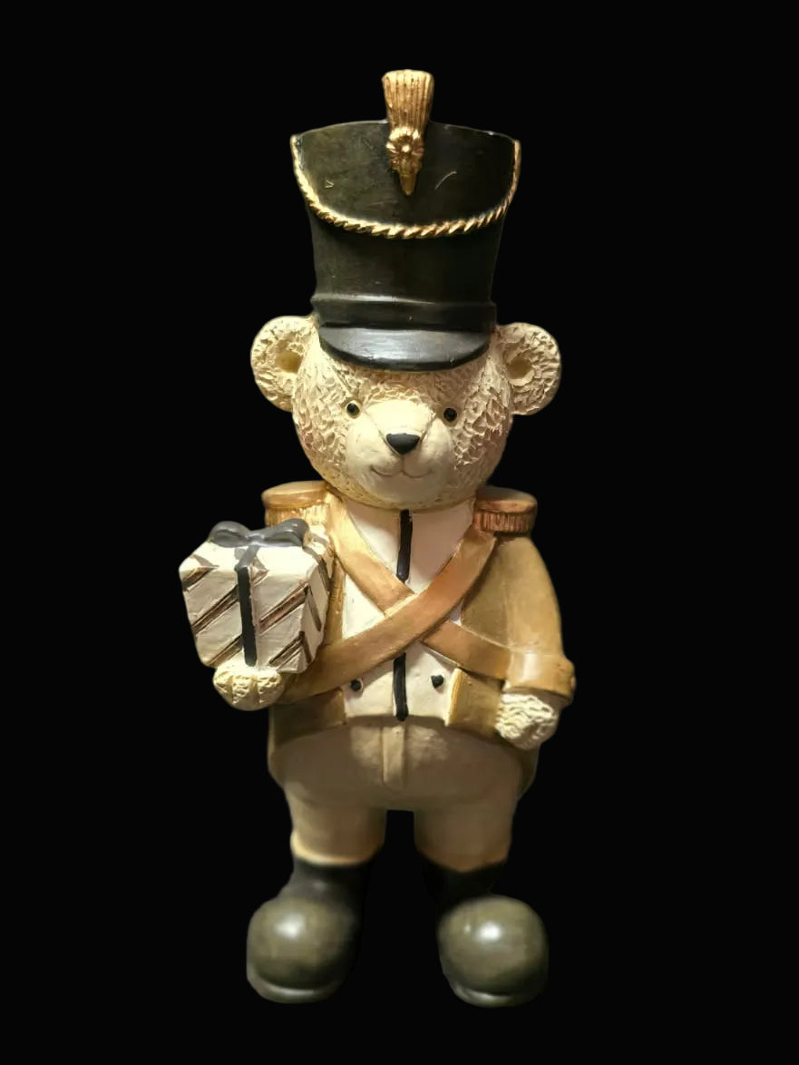 Teddy bear figurine dressed as a soldier holding a box on a dark background