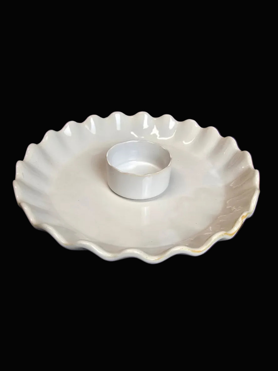 White ceramic dish with scalloped edge on a dark surface
