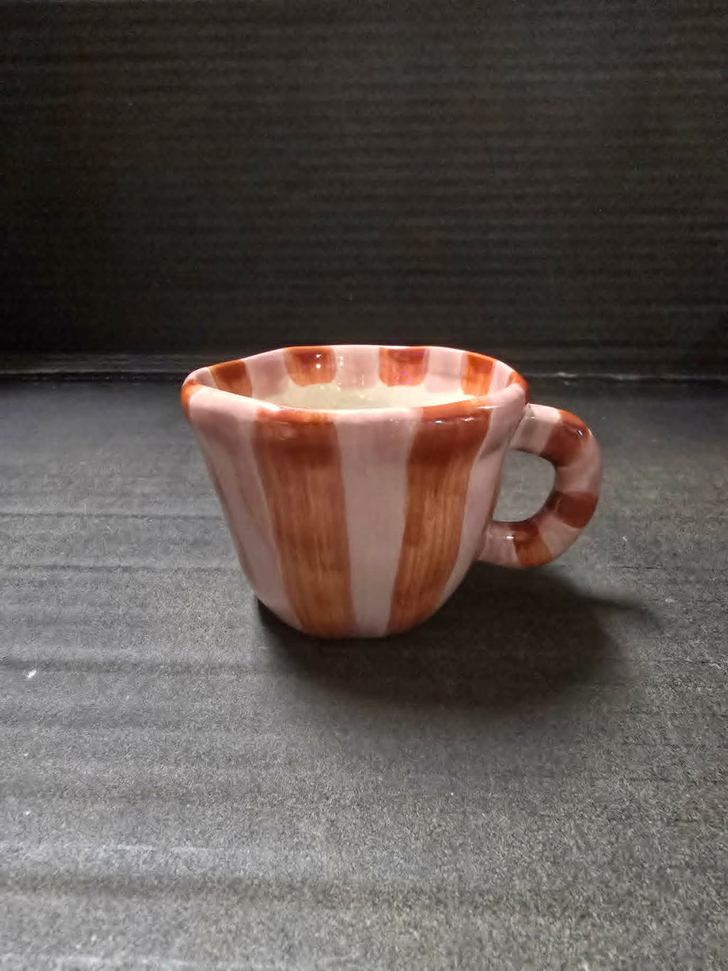 Ceramic mug with striped design on a textured surface
