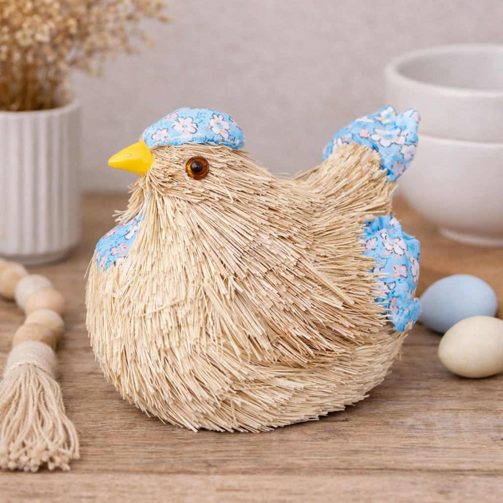 Blue floral straw chicken decoration with fabric cap and wings styled on a timber surface with pastel Easter eggs and a wooden bead garland — Mistletoe Home