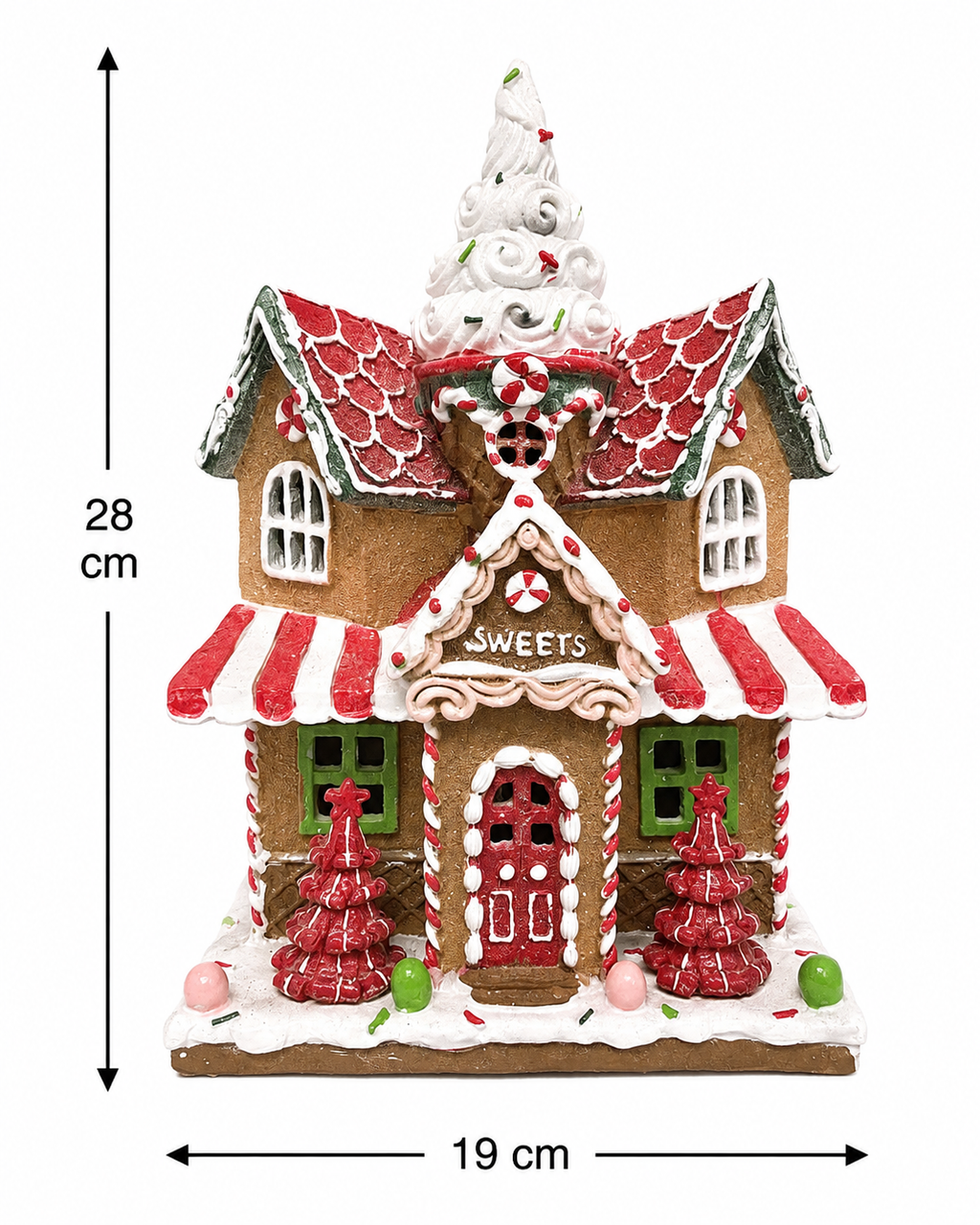Light-up gingerbread sweet shop Christmas house figurine displayed on a wooden table beside a lantern, candy cane, and Christmas tree