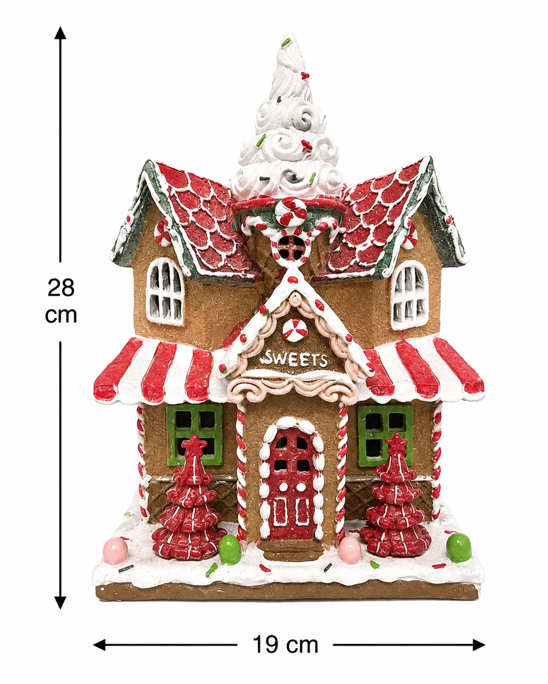 Light-up gingerbread sweet shop Christmas house figurine displayed on a wooden table beside a lantern, candy cane, and Christmas tree