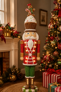 Light-up cupcake nutcracker Christmas figurine displayed beside a fireplace and Christmas tree with wrapped gifts
