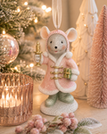 Pink cloak mouse with candle and gift hanging ornament displayed on a table beside a lit tree, bottle brush trees, and pink baubles