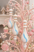 Pastel watercolour glass finial ornaments hanging on a pink candy-themed Christmas tree, showing the frosted white glass with pink, blue and mint swirl detailing and rose gold glitter bands