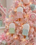 Pastel popsicle Christmas ornaments hanging on a pink flocked tree among candy and pastel baubles with fairy lights