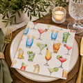 Watercolour cocktail print napkin folded on a plate with greenery, candle and wine glass at a table setting