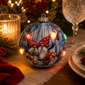 Light-up gnome Christmas bauble glowing on a table runner beside a candle, pine branches and red napkin, illuminated LED lights visible on the ornament
