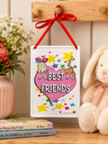 Cindy Lou and Max "Best Friends" tin hanging sign on a wooden hook beside flowers, a plush bunny and Dr. Seuss books