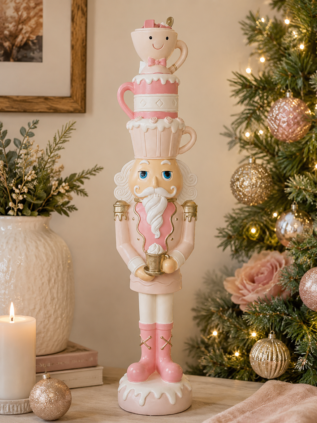 Pink Nutcracker Tea Cup figurine styled on a console table beside a Christmas tree, pink and gold teacup stack on its head, surrounded by candles and pink ornaments