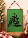 "'T was the night before Grinchmas" hanging sign displayed on a wooden shelf beside a frosted mini Christmas tree, wooden star, and lit lantern, red ribbon hanger and Grinch hand illustration visible.
