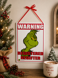 Grinch "Registered Regifter" tin sign hanging on a wall beside a Christmas tree, styled with pinecones, berries and a "Naughty is the New Nice" mug
