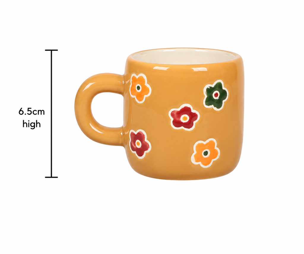 Mustard yellow ceramic mug with red, orange and green daisy detail on white background, showing handle and white interior glaze, 6.5cm high.