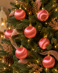 Pink silk baubles hanging on a Christmas tree with pinecones, ribbon, and warm fairy lights