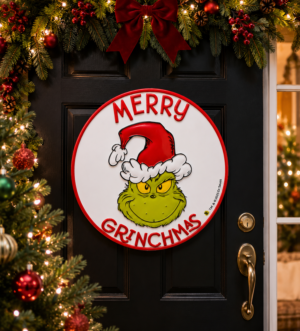 Merry Grinchmas round door sign hanging on a black front door, surrounded by Christmas garland, red bow, and berries
