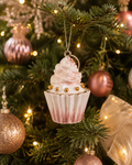 Pinecone swirl cupcake ornament hanging on a Christmas tree branch among blush baubles and a sheer gold ribbon