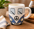Blue Kombi van ceramic mug filled with black coffee, styled on a wooden table with a plant, candle and books in a cosy home setting