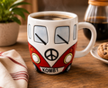 Red Kombi van ceramic mug filled with black coffee, styled on a wooden coffee table with a plant and magazine in a cosy living room