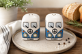 Kombi ceramic salt and pepper shaker set in blue and white, sitting on a cream speckled plate on a wooden table styled with bread, rosemary, and a striped linen