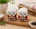 Red Kombi ceramic salt and pepper shaker set on a wooden board styled with rosemary, salt, pepper and a wicker basket