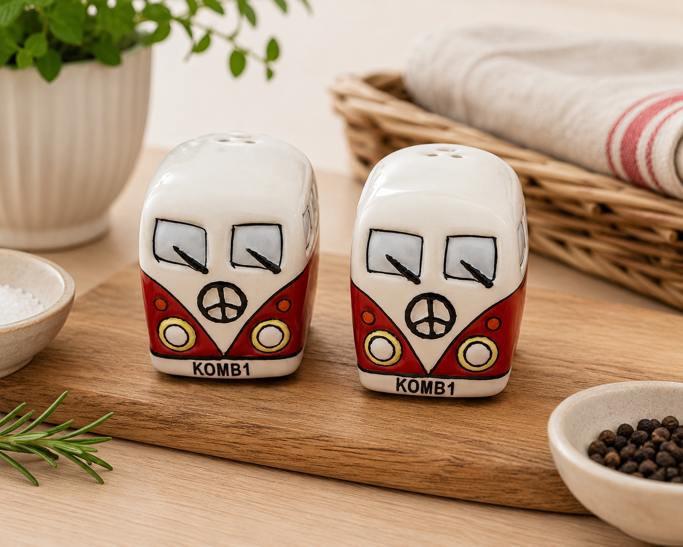 Red Kombi ceramic salt and pepper shaker set on a wooden board styled with rosemary, salt, pepper and a wicker basket