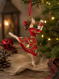 Clara the Ballerina resin Christmas ornament hanging on a Christmas tree, red dress with gold and green diamond detail, holding a nutcracker figurine, warm fairy lights in background