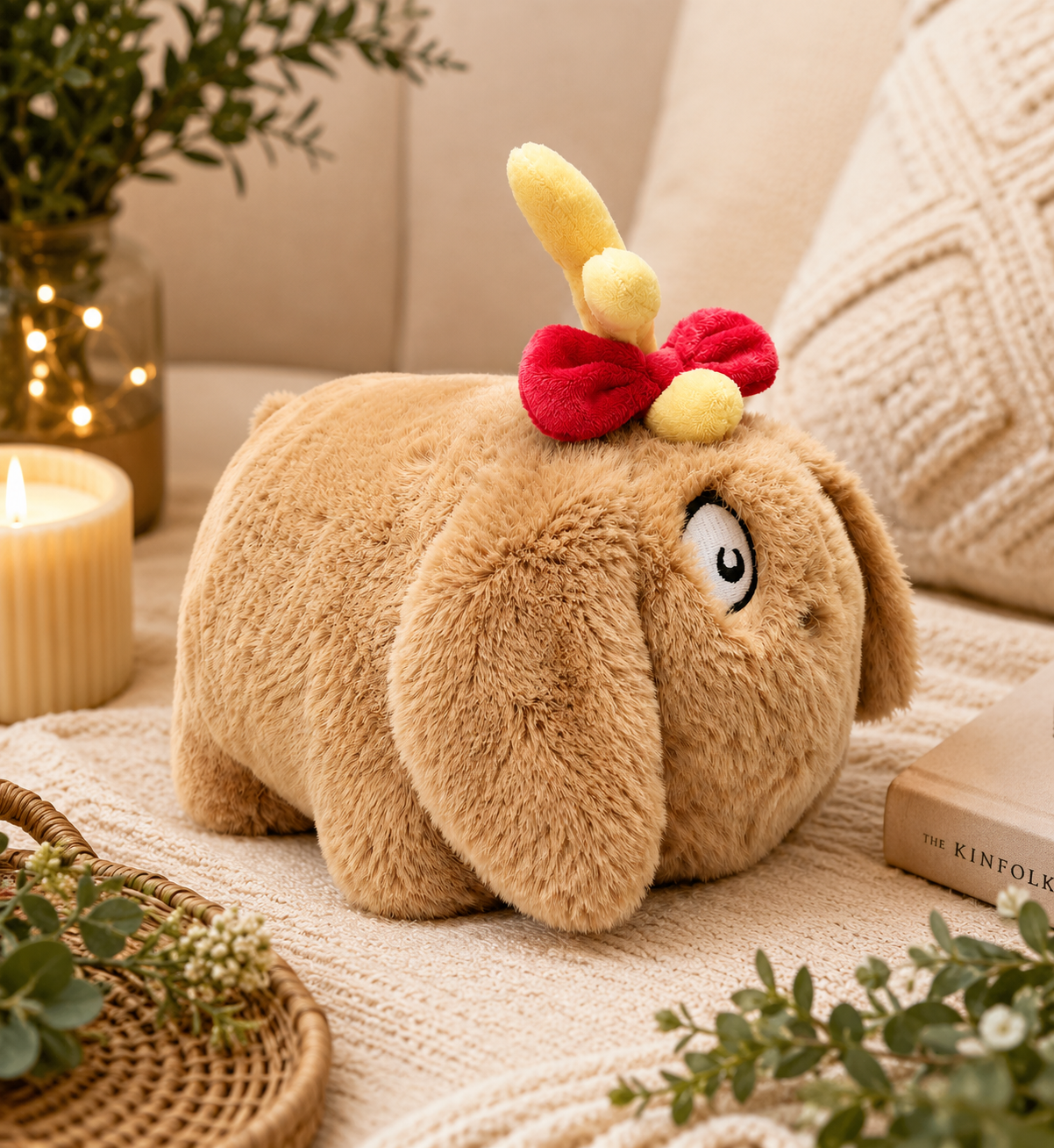 Max the Dog Spudster plush styled on a cream knit throw with a lit candle, fairy lights in a vase, and greenery — warm festive home setting