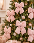 Multiple blush pink velvet bow decorations with satin ribbon hangers styled on a Christmas tree with rose gold and champagne baubles, fairy lights and wrapped pink gifts beneath — Mistletoe Home