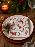 Christmas gnome print Gala paper napkin folded on a white ceramic plate on a red charger, styled on a timber Christmas table with a pine and red berry sprig, amber candle, crystal wine glass and festive garland — Mistletoe Home