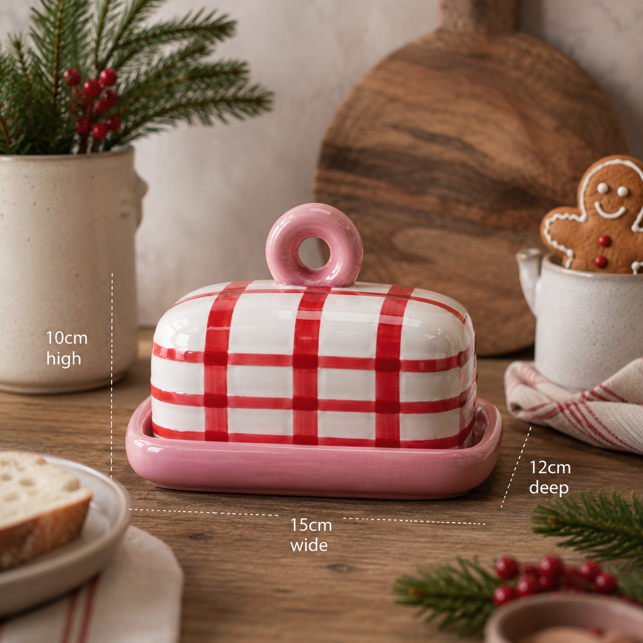 Red gingham ceramic butter dish with dimension overlay showing 15cm wide, 12cm deep and 10cm high, styled with Christmas greenery and gingerbread cookies