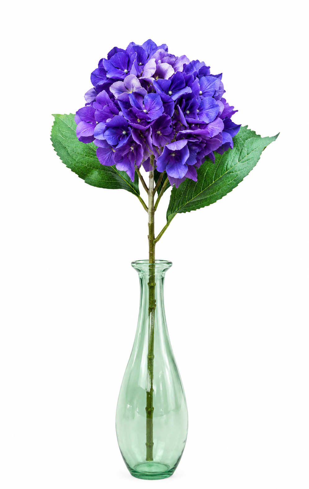 Single purple faux hydrangea stem with green leaves in a green glass vase on white background
