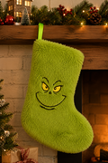 Grinch Christmas stocking hanging on a fireplace mantel with pine garland, red ornaments and warm fairy lights