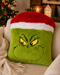 Large Grinch Santa hat plush cushion on a cream sofa next to a Christmas tree with red and gold ornaments