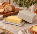 Crackle glaze ceramic butter dish open on a marble kitchen bench with a block of butter, sliced sourdough bread, sea salt, and honey nearby