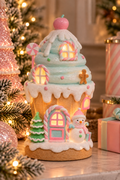 LED gingerbread cupcake house glowing warmly at night, pink and mint candy-themed Christmas decoration lit from inside, styled with pink Christmas trees and wrapped gifts