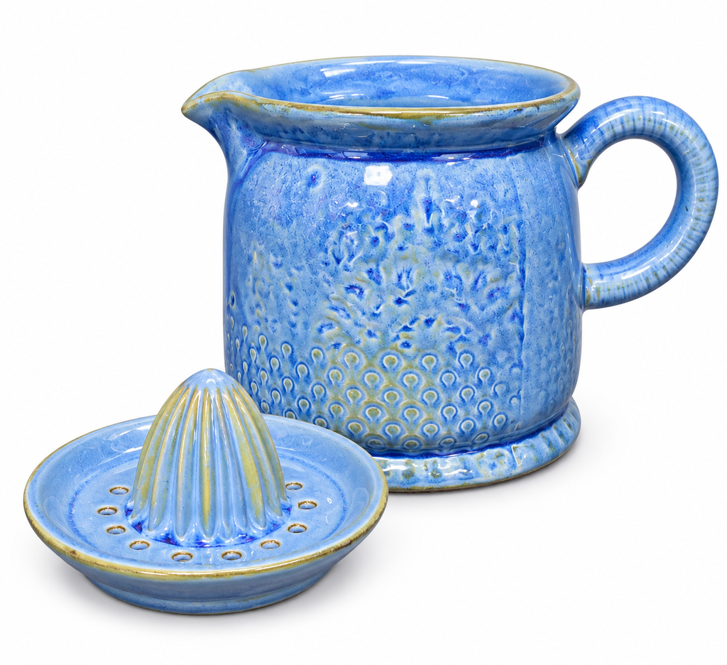 Blue ceramic citrus juicer shown disassembled on white background — pitcher base with pour spout and handle beside the separate perforated reamer top