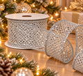 Silver sparkle mesh wired ribbon roll unspooling beside a lit Christmas tree, silver baubles, pinecones and gold wrapped gifts
