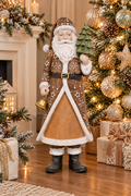 Rustic brown and white Santa figurine holding a mini Christmas tree and bell, displayed beside a gold-toned decorated Christmas tree with gift boxes