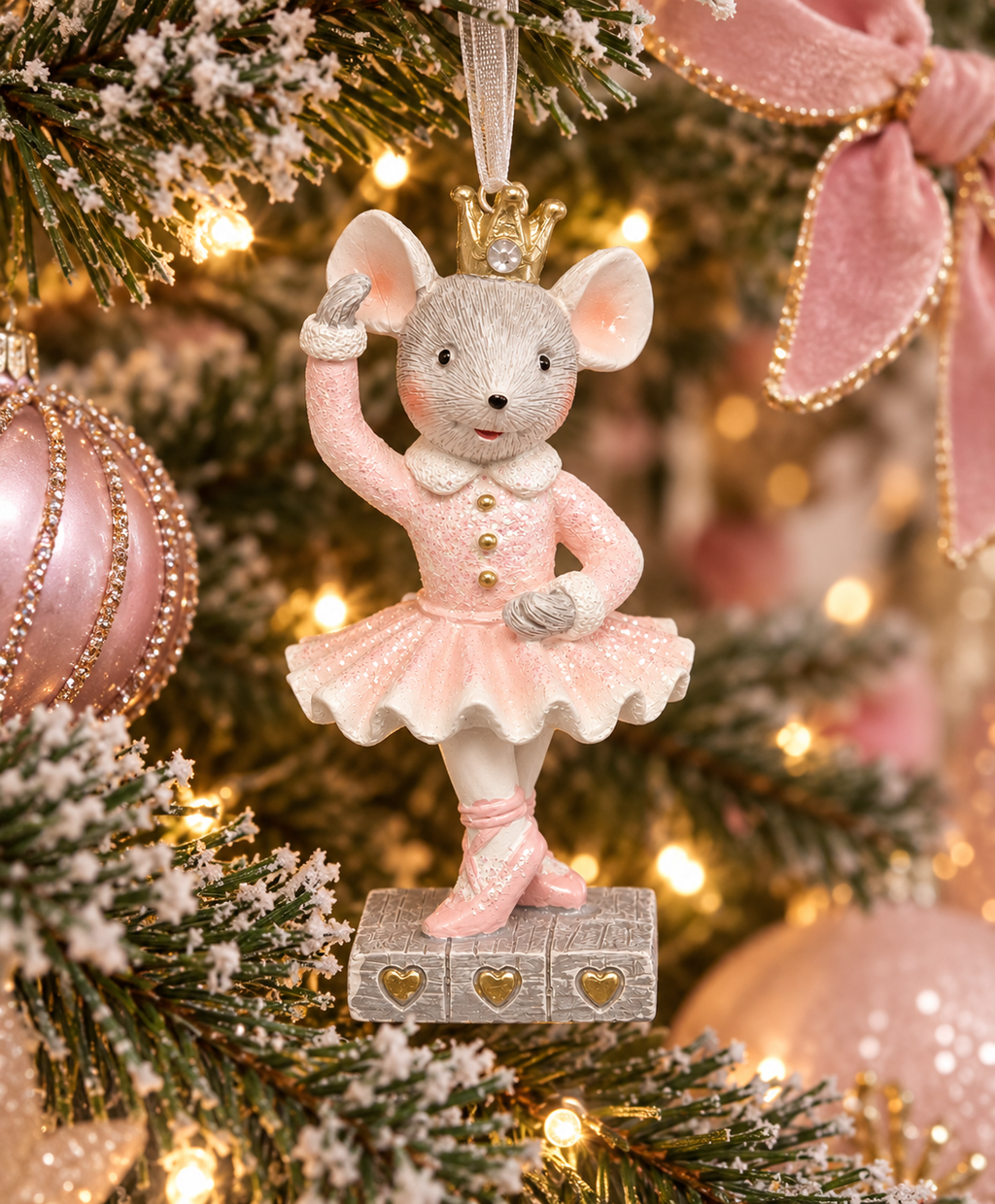 Pink ballerina mouse Christmas ornament hanging on a decorated tree with gold crown and glitter tutu, surrounded by pink baubles and fairy lights