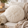 Round ivory faux fur cushion styled on a cosy sofa in neutral living room — Mistletoe Home Australia