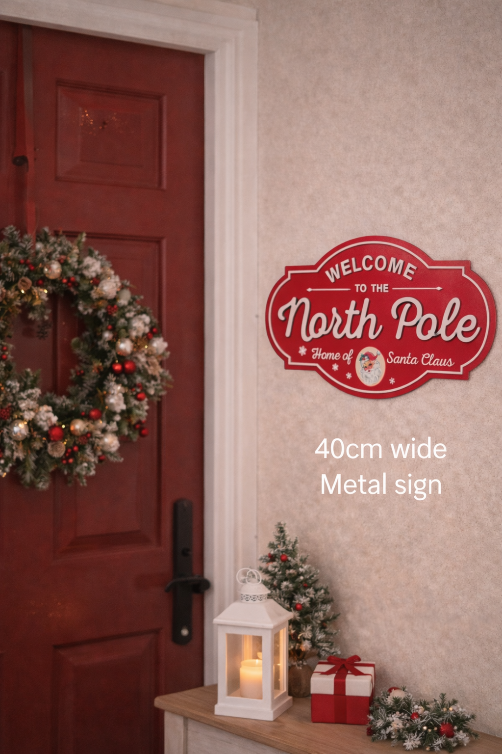 Welcome to the North Pole red metal Christmas sign 40cm x 24cm styled on a wall beside a red front door with Christmas wreath lantern and mini tree — Mistletoe Home Australia