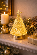 Gold crystal LED Christmas tree glowing warm white on a mantle styled with gold baubles, pine cones, frosted garland and a pillar candle — Mistletoe Home