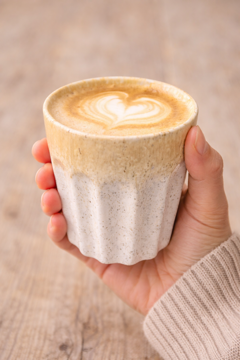 Hand holding speckled ceramic latte cup with scalloped base filled with heart latte art — coffee lover gift Australia Mistletoe Home