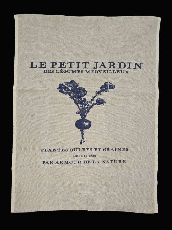 Flat lay of natural oatmeal linen tea towel showing full Le Petit Jardin Des Légumes Merveilleux navy botanical garden print on black background — Mistletoe Home