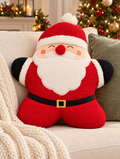 Santa Claus shaped red boucle cushion with white pompom hat, red pompom nose and fluffy white beard, styled on a cream sofa with a chunky knit throw, green velvet cushion and Christmas tree in the background