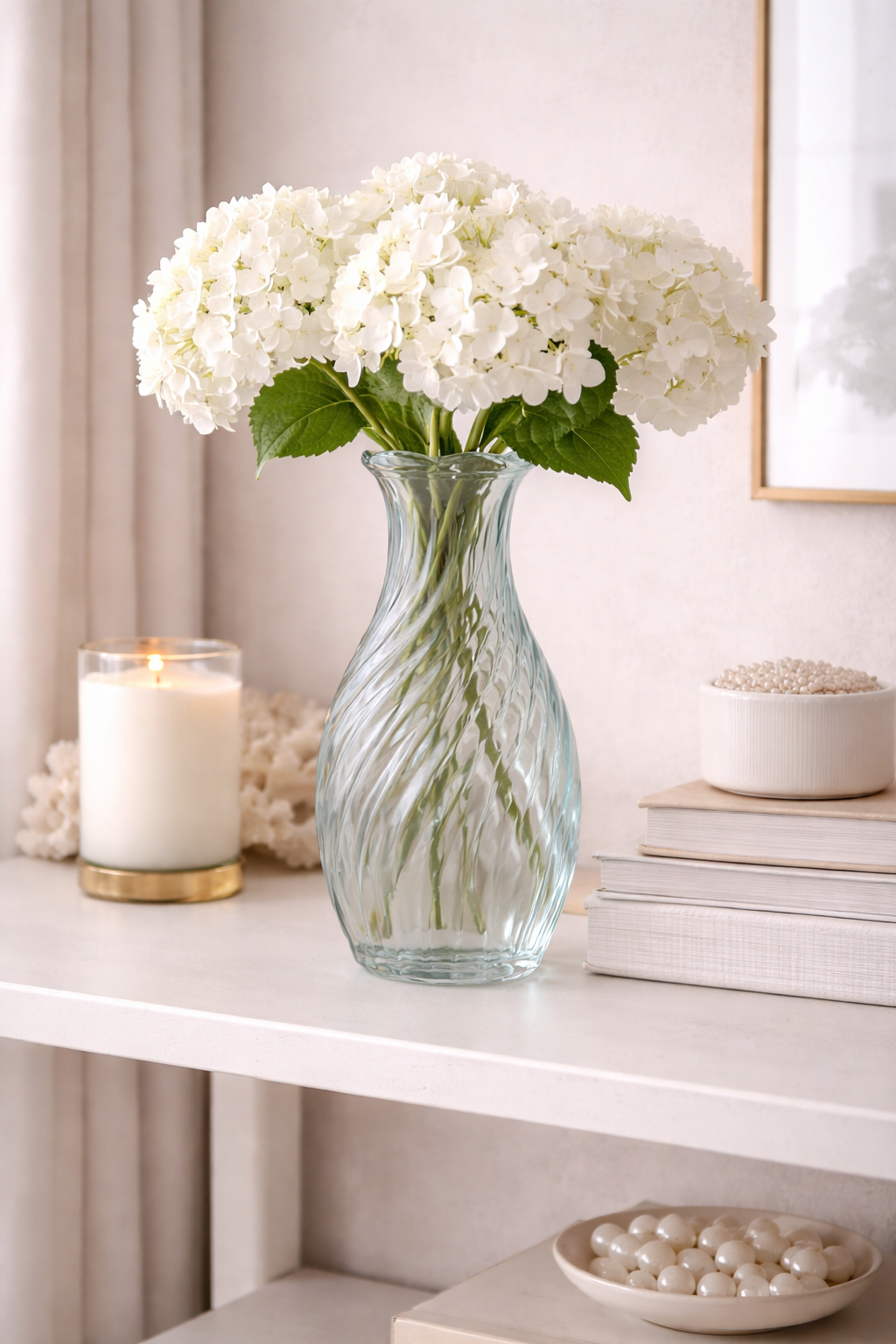 Blue twisted swirl glass vase with white hydrangeas styled on a white console table with a gold candle holder and pearl dish — Mistletoe Home