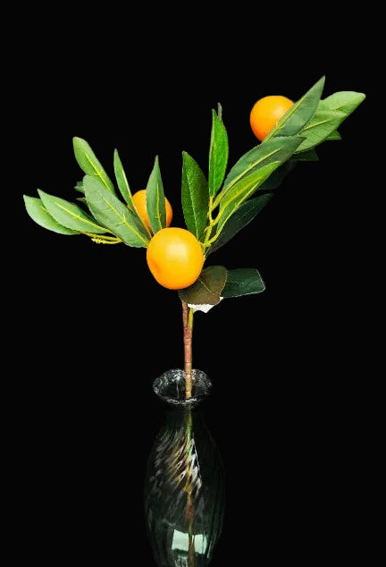 Green vase with mandarins and leaves against a dark background