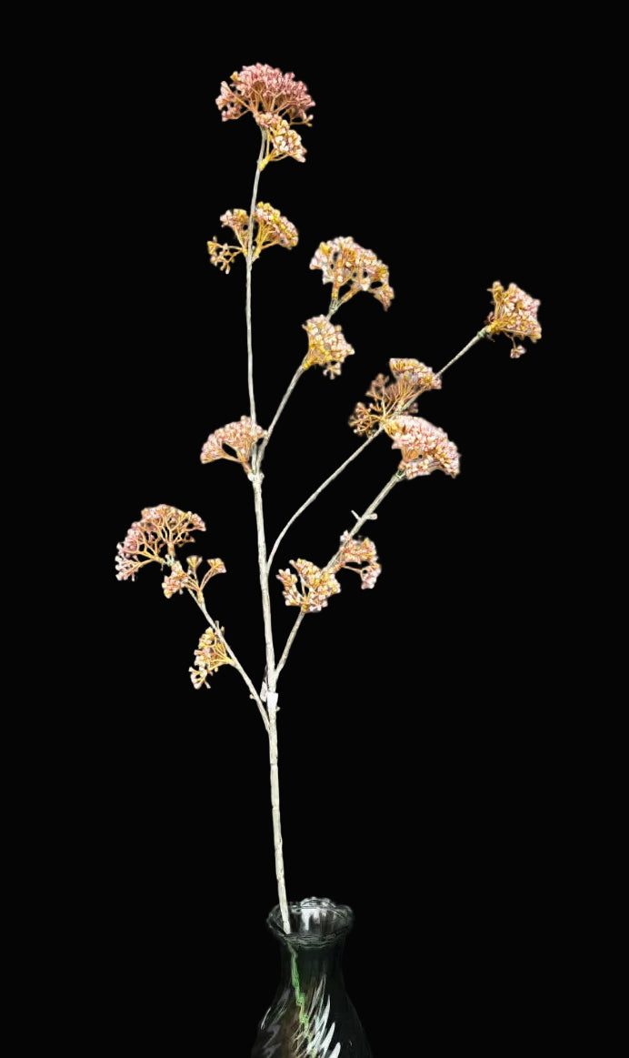 artificial flower branch in a glass bottle against a dark background