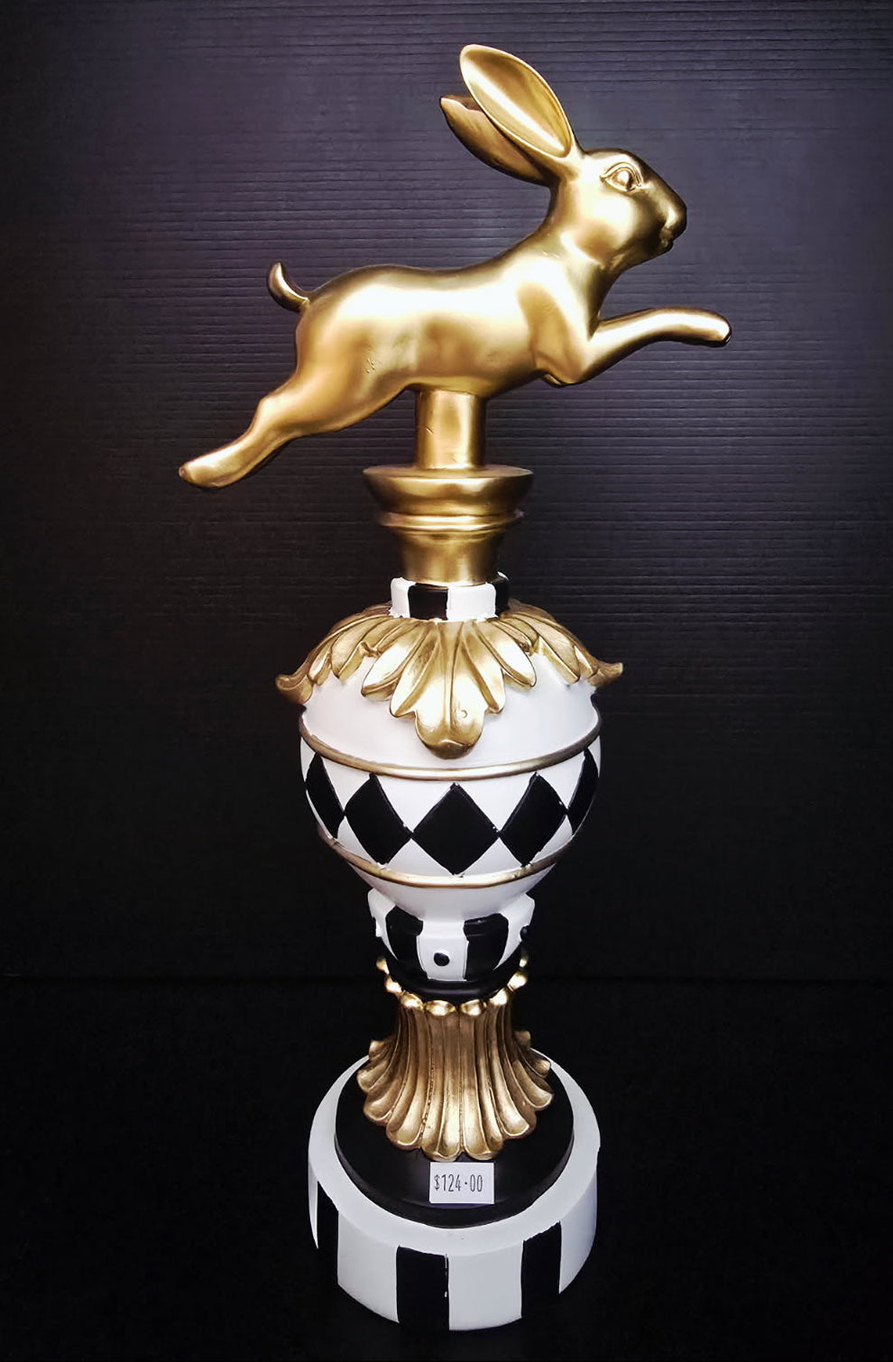 Decorative object with a gold rabbit on top against a dark background