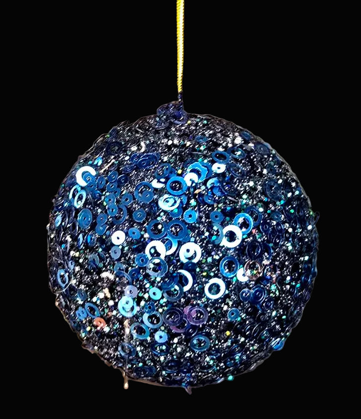 Decorative blue sequin ball hanging against a textured brown background